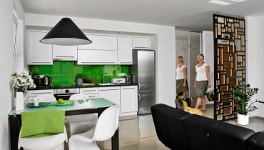 <B>Pani Agata, stomatolog, jest przyzwyczajona do chłodnych, sterylnych, łatwych do sprzątania wnętrz. I takie miało też być jej pierwsze mieszkanie. Żeby jednak nie wyglądało zbyt surowo i nie kojarzyło się z gabinetem, ożywiono je wyrazistymi motywami graficznymi i akcentami mocnych barw.</B> <BR />Sterylnie, ale nie surowo. Pani domu mało gotuje, aneks kuchenny jest więc niewielki. Zabudowa została zrobiona na wymiar z laminowanej płyty. Ożywczym elementem wystroju jest ściana nad blatem przykryta zielonym lakierowanym szkłem. Na podłodze - duże błyszczące płytki ułożone bez fug. Taką łatwą w pielęgnacji 'lustrzaną'  podłogę położono w całym mieszkaniu. Umowną granicą między kuchnią a pokojem jest stół, nad którym wisi lampa Cone Light projektu Toma Dixona. <B>Pani Agata, stomatolog, jest przyzwyczajona do chłodnych, sterylnych, łatwych do sprzątania wnętrz. I takie miało też być jej pierwsze mieszkanie. Żeby jednak nie wyglądało zbyt surowo i nie kojarzyło się z gabinetem, ożywiono je wyrazistymi motywami graficznymi i akcentami mocnych barw.</B> <BR />Sterylnie, ale nie surowo. Pani domu mało gotuje, aneks kuchenny jest więc niewielki. Zabudowa została zrobiona na wymiar z laminowanej płyty. Ożywczym elementem wystroju jest ściana nad blatem przykryta zielonym lakierowanym szkłem. Na podłodze - duże błyszczące płytki ułożone bez fug. Taką łatwą w pielęgnacji 'lustrzaną'  podłogę położono w całym mieszkaniu. Umowną granicą między kuchnią a pokojem jest stół, nad którym wisi lampa Cone Light projektu Toma Dixona.