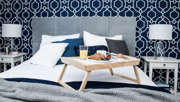 W sypialni najbardziej wyrazistym elementem jest tapeta o zdecydowanym wzorze i intensywnym kolorze. Nadmorskie mieszkanie inspirowane stylem Hampton