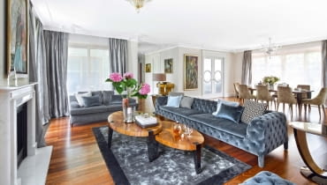 Salon połączony z jadalnią tworzy imponującą strefę dzienną. Od kuchni oddzielają go drzwi z dekoracyjnym motywem koła. Oświetlenie La Murrina i Baccarat. Podłoga (w całym apartamencie) z naturalnego orzecha amerykańskiego (Kahrs).