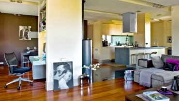 <b> WOKÓŁ KOMINKA. Mąż robi kawę, żona pracuje przy komputerze, dziecko ogląda bajkę. Rodzina jest razem, ale każdy może robić coś innego, nie przeszkadzając reszcie domowników. To efekt umiejętnego podziału przestrzeni dziennej na strefy funkcjonalne. </b> Otwarta część dzienna zajmuje aż dwie trzecie całego mieszkania - niecałe 60 m kw. Urządzono ją tak, by rodzina mogła przebywać razem, mając zapewnione dobre warunki nie tylko do odpoczynku, ale również do pracy. Po połączeniu kuchni z pokojem na środku wnętrza pozostał komin, który został pomysłowo obudowany - powstało tu m.in. miejsce na komputer. Konstrukcja ta umownie wyznacza podział na poszczególne strefy: wypoczynkową, kuchenną i jadalną. Odrębność funkcji podkreśla podłoga ułożona z trzech różnych materiałów (drewno, kamień i płytki gresu). Granicę między kuchnią a kątem wypoczynkowym dodatkowo zaznaczają reflektorki halogenowe zainstalowane w wąskiej długiej wnęce w podwieszanym suficie. <BR /> W aneksie kuchennym zaplanowano wiele schowków ułatwiających utrzymanie porządku: ciąg szafek dolnych i górnych, sięgającą sufitu zabudowę przy bocznej ścianie oraz wyspę z szafką w formie słupa, przesłaniającą zlewozmywak. Do fornirowanych bielonym dębem frontów mebli dobrano kontrastujący blat z granitu. Podłogę w kuchni wyłożono praktycznym gresem.