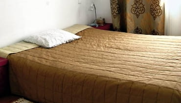 PRZED ZMIANĄ. Do niewielkiej sypialni właścicielka wstawiła jedynie łóżko. Przykryła je pikowaną narzutą w tabaczkowym kolorze. Z tkaniny o takim samym odcieniu uszyła zasłony.