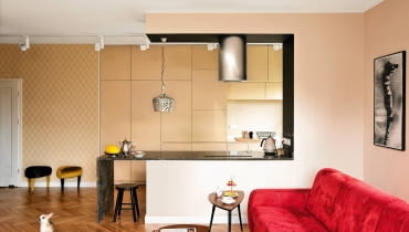 <B>W wystroju swojego mieszkania Justyna połączyła różne konwencje aranżacyjne, wybierając z nich to, co najlepsze. Ukłonem w stronę minimalizmu jest nieprzeładowana sprzętami, otwarta przestrzeń, do dawniejszych stylów nawiązuje ciepła kolorystyka i przyciągające wzrok formy. Efekt? Przytulne, odbiegające od sztampy wnętrze.</B> <p> </p> <BR />Po połączeniu salonu z?kuchnią i przedpokojem powstała przestronna strefa dzienna, na czym Justynie bardzo zależało. W wystroju wnętrza umiejętnie zestawiono różne style: minimalistyczna zabudowa kuchenna zgodnie egzystuje z tapetą w?motywy inspirowane wzornictwem z?okresu art déco, ikeowskimi stolikami stylizowanymi?na lata sześćdziesiąte XX?wieku, podłogą ułożoną w?oldschoolową jodełkę i?secesyjnymi naczyniami - pamiątkami rodzinnymi. Wiszący nad kanapą obraz?Józefa Krzysztofa Oraczewskiego gospodyni dostała od?rodziców. wystrój wnętrz, kuchnia otwarta, aneks kuchenny