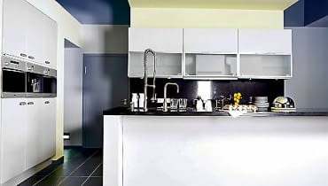 Jedną ścianę zabudowano od podłogi do sufitu. Wbudowany sprzęt tworzy z szafkami idealną płaszczyznę. Zlew i kuchenkę umieszczono w wyspie wysuniętej na środek pomieszczenia. Jedną ścianę zabudowano od podłogi do sufitu. Wbudowany sprzęt tworzy z szafkami idealną płaszczyznę. Zlew i kuchenkę umieszczono w wyspie wysuniętej na środek pomieszczenia.