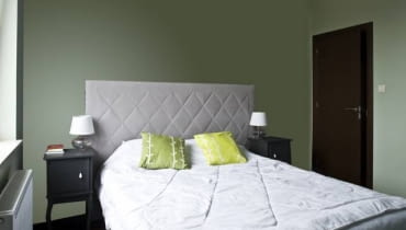 SYPIALNIA PRZED ZMIANĄ. Łóżko z pikowanym zagłówkiem, stylizowane szafki nocne o ciekawej formie - takie meble domagały się odpowiedniej oprawy. Stylistka, która podjęła się metamorfozy sypialni, mogła wydać nie więcej niż 1500 zł. I tyle wystarczyło, bo wyobraźnia, w przeciwieństwie do budżetu, nie ma granic. Gospodarze wybrali ładne i wygodne meble, nie mieli jednak pomysłu, jak udekorować wnętrze. Raziły przede wszystkim pomalowane na pistacjową zieleń puste ściany i brak tkanin - nieodzownych w tworzeniu przytulnej atmosfery.