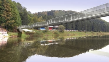 Tak ma wyglądać kładka nad jeziorem Bystrzyckim w Zagórzu Śląskim. W powietrzu kładkę będzie utrzymywać kilkanaście lin zakotwiczonych w skałach. Będzie miała prawie 126 m długości, 2,4 m szerokości na węższych odcinkach i do 4,9 m w miejscach, gdzie staną ławy Tak ma wyglądać kładka nad jeziorem Bystrzyckim w Zagórzu Śląskim. W powietrzu kładkę będzie utrzymywać kilkanaście lin zakotwiczonych w skałach. Będzie miała prawie 126 m długości, 2,4 m szerokości na węższych odcinkach i do 4,9 m w miejscach, gdzie staną ławy