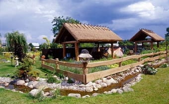 Zagroda- -skansen. Pod wiatami krytymi trzcinową strzechą właściciel gromadzi stary, nieużywany sprzęt rolniczy. OGROD SKANSEN