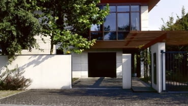 Widok na dom od strony ulicy. Za przeszklonymi ścianami na piętrze zaplanowano pracownię plastyczną. Drugi podobny szklany kubik od strony skarpy mieści jadalnię