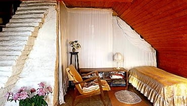 Na strychu wokół rozłożystego pobielonego komina urządzono trzy niewielkie sypialnie dla gości. Oddzielają je od siebie jedynie udrapowane jasne tkaniny. Białe ''schodki'' to element konstrukcyjny komina OKOLICE WARSZAWY - DOM EMILII KRAKOWSKIEJ NAD RZEKA SWIDER FOT. RAFAL LIPSKI UWAGA ! PONOWNA PUBLIKACJA ZA ZGODA WLASCICIELKI ! PUBLIKACJA CZTERY KATY NR 9 (144) - 9.2003