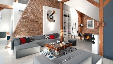 Ceglana ściana oddziela strefę dzienną od zabudowanej sypialni. Między sofami Carmo (BoConcept) stolik zaprojektowany w studio Cuns. Na ścianie obraz Małgorzaty Chmielowskiej. aranżacja wnętrz, prezentacje mieszkań, wystrój wnętrz