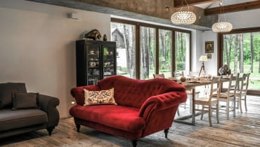 JADALNIA. Na granicy jadalni i części wypoczynkowej stoi reprezentacyjna pikowana kanapa. Żywy kolor mebla wybrano specjalnie, by przełamać wszechobecne brązy i szarości.