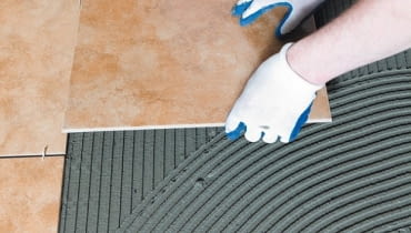 Płytki układa się na równo rozprowadzonej warstwie zaprawy klejącej. układanie płytek, płytki ceramiczne