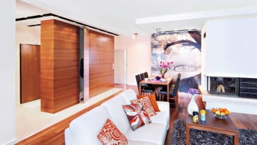 Gospodarze, którzy lubią przestronne i jasne wnętrza, zdecydowali się połączyć salon z przedpokojem i kuchnią. Uzyskanej w ten sposób strefy dziennej nie zamierzali zagracać masywnymi wolno stojącymi meblami do przechowywania. Z drugiej strony zdawali sobie sprawę, że są one w domu konieczne. Dylemat rozwiązała projektantka, proponując zbudowanie meblościanki, która oddzieliłaby strefę wypoczynkową od przedpokoju, a jednocześnie zapewniła wygodne schowki. Pojemną szafę, sięgającą od podłogi do sufitu, zrobiono z płyty fornirowanej egzotycznym tekiem (z tego samego drewna jest parkiet). Gospodarze, którzy lubią przestronne i jasne wnętrza, zdecydowali się połączyć salon z przedpokojem i kuchnią. Uzyskanej w ten sposób strefy dziennej nie zamierzali zagracać masywnymi wolno stojącymi meblami do przechowywania. Z drugiej strony zdawali sobie sprawę, że są one w domu konieczne. Dylemat rozwiązała projektantka, proponując zbudowanie meblościanki, która oddzieliłaby strefę wypoczynkową od przedpokoju, a jednocześnie zapewniła wygodne schowki. Pojemną szafę, sięgającą od podłogi do sufitu, zrobiono z płyty fornirowanej egzotycznym tekiem (z tego samego drewna jest parkiet).