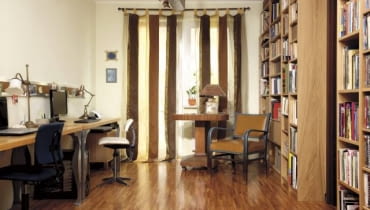 Dekoracja okna to jeden z elementów ocieplających to pomieszczenie. Dzięki lekko prześwitującym zasłonom do wnętrza wpada dzienne światło, ale słońce nie odbija się w monitorach. Na podłodze efektownie prezentuje się parkiet przemysłowy.