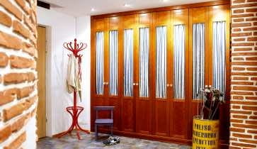 Ceglane ściany w przedpokoju mają nierówną powierzchnię, a dzięki temu - ciekawą fakturę. Jedną ścianę w całości zabudowano nietypowymi przeszklonymi szafami.