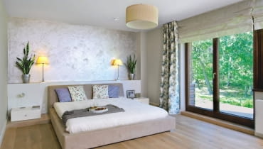 Dom miał być przytulny, urządzony z wyraźną przewagą naturalnych materiałów: drewna, wikliny i bawełny, ale też z nutą nowoczesności. Właścicielom, Monice i Adamowi, udało się spełnić to marzenie. <BR /> DOM. Sypialnia, podobnie jak cały dom, jest utrzymana w stonowanych brązach, beżach i bielach. Spokojny wystrój ożywiają kwiaty - zarówno te prawdziwe, jak i na tkaninach. Ścianę za łóżkiem wykończono tynkiem strukturalnym. Zabudowa z lakierowanego na biało drewna, pełniąca funkcję półki, kryje kable zasilające lampki.