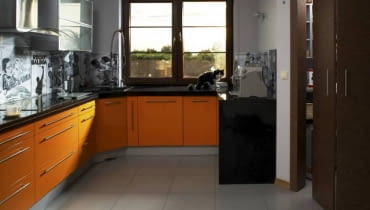 KUCHNIA. Narażone na zabrudzenie ściany nad blatem roboczym zostały wykończone w bardzo niebanalny sposób. Wyklejono je starymi, czarno-białymi plakatami filmowymi i muzycznymi, a następnie zabezpieczono przed zniszczeniem taflami przezroczystego szkła. WNETRZA KUCHNIA MEBLE