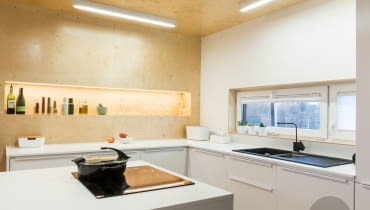 Podświetlana wnęka w kuchni jest ważnym elementem dekoracyjnym w kuchni. Kuchnia jest jedynym pomieszczeniem, w którym sklejka jest nie tylko na ścianie, ale także na suficie. Mieszkanie całe w sklejce