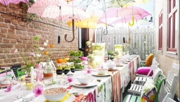 W upalny słoneczny dzień zastawiony stół na balkonie lub tarasie mogą ocieniać... parasole przyniesione przez gości, zawieszone na przeciągniętych nad stołem sznurkach. Nie tylko ochronią przed słońcem, ale też będą efektowną dekoracją.