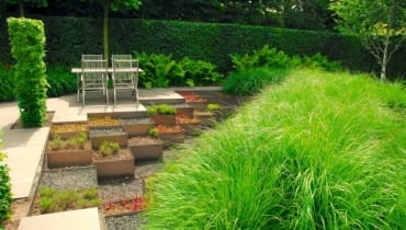 Sprytne rozwiązanie - ogród z 'samoobsługowych' sukulentów w aluminiowych skrzyniach i gigantyczej rabaty z trwałych ozdobnych traw.