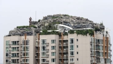 Dwupiętrowa rezydencja na szczycie 26-piętrowego wieżowca. This Aug. 12, 2013 photo released by Chinas Xinhua News Agency shows a residential building with a rocky style villa on its roof, in Haidian District of Beijing, China. Beijing authorities are planning to demolish the bizarre rooftop villa embedded in rocks, trees and bushes that allegedly was built illegally atop a 26-story apartment block in the capital. (AP Photo/Xinhua, Luo Xiaoguang) NO SALES