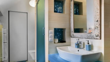 ZA MUROWANĄ KABINĄ PRYSZNICOWĄ dyskretnie ukryto podwieszony sedes. W łazience nie trzeba było szukać miejsca na pralkę - za przesuwanymi drzwiami znajduje się niewielkie pomieszczenie gospodarcze, które pełni m.in. funkcję domowej pralni. łazienka