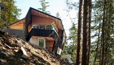 Oryginalna bryła budynku, przypominająca heksagon, to dzieło projektantów ze studia Battersby Howat Architects z pobliskiego Vancouver. Przestrzenny wielokąt zapewnia doskonały widok na całą okolicę. Stromo nachylony i zalesiony stok, u stóp którego znajduje się mała kamienna plaża, okazał się idealnym miejscem na budowę domu dla całej rodziny.