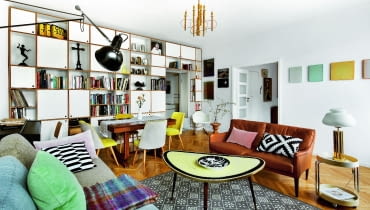 Ściana oddzielająca salon od przedpokoju zabudowana jest regałem ze sklejki (Intterno Home). Na półkach m.in. renesansowy krucyfiks i kolekcja bauhausowskich dzbanków. Pozostałe meble to vintage, w większości z lat 60. regały na książki