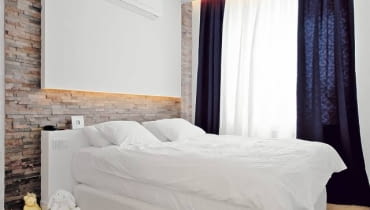 Sypialnia. Ścianę za łóżkiem obłożono naturalnym łupkiem. Zastosowano łatwe do układania płytki o wymiarach 60 x 15 cm - każda z nich jest zrobiona z nierównych pasków kamienia połączonych żywicą poliestrową. WNETRZA , POKOJ , SYPIALNIA - LOZKO