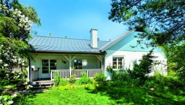 Parterowy murowany dom otynkowano na biało i ozdobiono detalami z drewna, co nadało całości malowniczy charakter wiejskiego siedliska dom jednorodzinny, dom parterowy, dom z udogodnieniami dla niepełnosprawnych