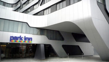 Widok na wejście główne hotelu Park Inn. Po prawej przejazd pod skrzydłem hotelowym w formie leja wyżłobionego w bryle budynku. Ovotz design lab., jurgen mayer, hotel, kraków, Park Inn, architektura, projekt, futuryzm, elewacja