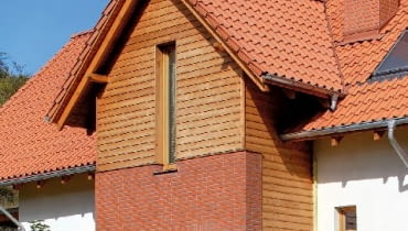 Przed zamontowaniem desek oblicówki, na styku elewacji klinkierowej i drewnianej należy zamontować listwę okapową, chroniącą przed zaciekaniem wody pod ocieplenie ze styropianu - może to być okapnik z blachy powlekanej lub pasek papy wywinięty na dekoracyjną deskę okapową. Przed zamontowaniem desek oblicówki, na styku elewacji klinkierowej i drewnianej należy zamontować listwę okapową, chroniącą przed zaciekaniem wody pod ocieplenie ze styropianu - może to być okapnik z blachy powlekanej lub pasek papy wywinięty na dekoracyjną deskę okapową.