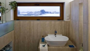 Projektowanie wnętrz. Łazienkę wykończono gresem do złudzenia przypominającym trawertyn (ma nawet tak samo jak ten kamień porowatą powierzchnię). Jednakowe płytki położone na ścianach i podłodze - to często stosowany trik optycznie powiększający wnętrze. WNETRZA , LAZIENKA