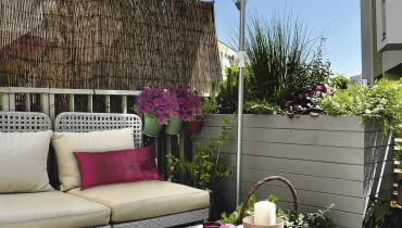 Kącik do relaksu - od strony chodnika przed wzrokiem przechodniów chroni mata i wysoka skrzynia dla roślin. W upały cień zapewnia jasny parasol. Kącik do relaksu - od strony chodnika przed wzrokiem przechodniów chroni mata i wysoka skrzynia dla roślin. W upały cień zapewnia jasny parasol.