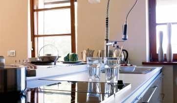 Zabudowa tworząca kuchenną wyspę jest zrobiona z takiego samego drewna jak meble w salonie. Dzięki temu wnętrza stanowią jednolitą stylistycznie całość.