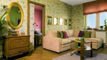 Zanim mieszkanie eksplodowało barwami, było w miarę spokojne i neutralne. Pani domu urządziła samodzielnie kuchnię z pomarańczowymi akcentami oraz biało-czerwoną łazienkę - i wciąż jej czegoś brakowało. Z radością przyjęła sugestię projektantki, aby wnętrza całkowicie Wypełnić barwami. I przełamać nowoczesność nutką romantyzmu. <BR /> MIESZKANIE. Tapeta w romantyczny kwiecisty wzór znalazła się nie tylko na ścianach, ale też na przesuwanych drzwiach do sypialni. Rzeźbioną komódkę kupiono na internetowej aukcji; w towarzystwie palmy i lustra w złoconych ramach zyskała iście salonowy charakter. Nad narożną kanapą - oprawione w jednakowe ramki fotografie w sepii, umieszczone na tle zielonego passe-partout. pokój dzienny, tapeta, salon