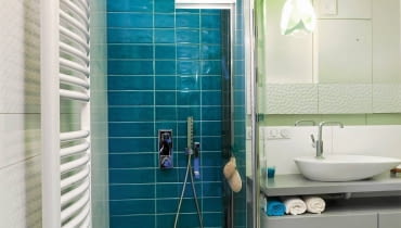 ŁAZIENKA. Kolorystyka wnętrza miała się kojarzyć z wypoczynkiem nad wodą. I tak właśnie jest dzięki zestawieniu dwóch barw - błękitu i bieli. Pas mozaiki w morskich odcieniach prowadzi od drzwi wejściowych wprost do kabiny prysznicowej. Na pozostałej części podłogi ułożono deski z drewna teku, które jest odporne na działanie wody (dodatkowo zostało zaolejowane). ŁAZIENKA. Kolorystyka wnętrza miała się kojarzyć z wypoczynkiem nad wodą. I tak właśnie jest dzięki zestawieniu dwóch barw - błękitu i bieli. Pas mozaiki w morskich odcieniach prowadzi od drzwi wejściowych wprost do kabiny prysznicowej. Na pozostałej części podłogi ułożono deski z drewna teku, które jest odporne na działanie wody (dodatkowo zostało zaolejowane).