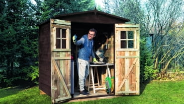 Drewniany domek na narzędzia (180×180 cm), z dwuskrzydłowymi drzwiami i dwuspadowym daszkiem krytym papą. Ok. 1200 zł, Castorama