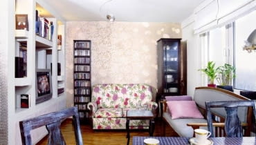 Romantyczny kącik wypoczynkowy - sofa obita tkaniną w kolorowe róże, a w tle tapeta (również w kwiatowy wzór, tyle że w srebrzystych barwach). Na podłodze parkiet przemysłowy. UWAGA PONOWNA PUBLIKACJA ZA ZGODA WLASCICIELI