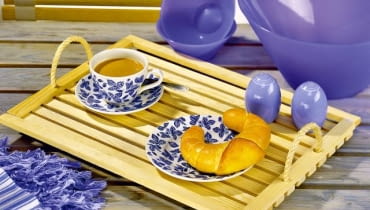 Z prześwitami. Do drewnianej ramki (kupionej w sklepie lub zrobionej samodzielnie) przybijamy od spodu listewki, zostawiając między nimi 5-milimetro-we odstępy. W krótszych bokach tacy wiercimy otwory i mocujemy w nich uchwyty z grubego sznura. Całość lakierujemy.