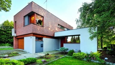 Widok na elewację frontową od strony ulicy. Układ brył budynku jest konsekwencją ukształtowania terenu działki elewacja frontowa, nowoczesny dom