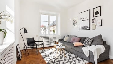 W salonie nad kanapą zawieszono proste grafiki. Białe mieszkanie w stylu skandynawskim