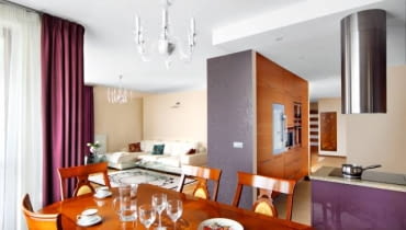 <b> RAZEM, A JEDNAK ODDZIELNIE. Wyraźny podział przestrzeni w części dziennej uzyskano dzięki zastosowaniu różnych barw, stylów i materiałów. Optyczne strefy wzmocniono, stawiając przegrody meblowe. W efekcie żaden z aneksów o odmiennych funkcjach nie koliduje ze sobą. </b> <BR /> Właścicielka mieszkania zdecydowała się na połączenie pokoju z kuchnią i przedpokojem, mimo obaw, że dwa ostatnie pomieszczenia będą dominować nad częścią salonową. Zawierzyła projektantce, która zapewniła ją, że tak się nie stanie. Kąt wypoczynkowy został oddzielony od aneksu kuchennego i od przedpokoju wysokimi ściankami, przy których zbudowano pojemne schowki. Jadalnię urządzono w obszernej wnęce niedaleko kuchni. Chociaż strefy jadalnej nie wydzielają dodatkowe przegrody, to jej odrębność jest wyraźna - podkreślają ją eleganckie stylizowane meble, które kontrastują z prostymi formami elementów wyposażenia w pozostałych częściach wnętrza. Kuchni nie widać ze strefy wypoczynkowej - zasłania ją wysoka zabudowa ze schowkami i urządzeniami AGD: piekarnikiem, kuchenką mikrofalową, ekspresem do kawy oraz lodówką i chłodziarką do wina. Strefę tę dodatkowo wyodrębnia podwieszany sufit i podłoga - płytki gresu dopasowane barwą do dębowego parkietu w salonie (gres położono też w części wejściowej przedpokoju).