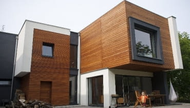 Nadwieszona część bryły sypialni na piętrze tworzy zadaszenie tarasu na parterze, umożliwiając korzystanie z niego nawet w deszczowe dni Nadwieszona część bryły sypialni na piętrze tworzy zadaszenie tarasu na parterze, umożliwiając korzystanie z niego nawet w deszczowe dni