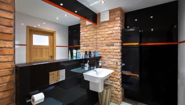 Niektóre fragmenty ścian zostały pokryte cegłą, która przełamuje nowoczesną i chłodną stylistykę. łazienka, meble łazienkowe, wystrój wnętrz