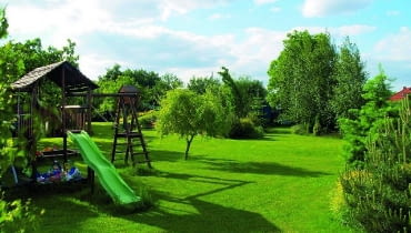 Grupy roślin ozdobnych rozmieszczono na obrzeżach trawnika. Dzięki temu dzieci mają duży teren do zabawy. A w przyszłości w miejscu zjeżdżalni, drabinki do wspinania i piaskownicy będzie można utworzyć nowe rabaty