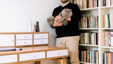 NASZ GOŚĆ. Pan Wojciech z kotem Lolkiem przy jednym z zaprojektowanych przez siebie mebli - sekretarzyku. Jak wspomina pan Wojtek, szukanie rzemieślnika, który podjąłby się ręcznego toczenia i polerowania aluminiowych uchwytów, trwało cztery miesiące. Ale było warto, bo przecież diabeł tkwi w szczegółach... A gospodarz przywiązuje do detali ogromną wagę. OLYMPUS DIGITAL CAMERA