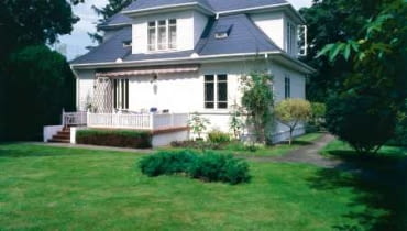 Drewniany modrzewiowy dom otoczony ogrodem utrzymanym w charakterze parku. Kilka lat temu elewację budynku pomalowano na biało, a dach pokryto łupkiem w kolorze grafitu układanym na łatach i kontrłatach przybitych do papy na deskowaniu. Drewniany modrzewiowy dom otoczony ogrodem utrzymanym w charakterze parku. Kilka lat temu elewację budynku pomalowano na biało, a dach pokryto łupkiem w kolorze grafitu układanym na łatach i kontrłatach przybitych do papy na deskowaniu.