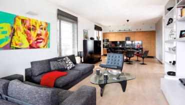 W kuchni zainstalowano listwy oświetleniowe z halogenami, nad stołem jest lampa wisząca, a w części wypoczynkowej - kinkiety i reflektorki. We wnętrzu dominują ciemne szarości i czerń rozjaśnione dużymi płaszczyznami bieli i kremowego beżu.