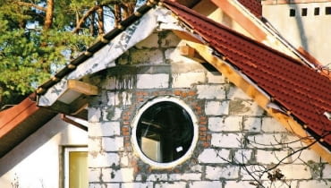 Okrągły otwór na okno wycięto w ścianie z betonu komórkowego. Belka nadprożowa jest powyżej okrągłe okno,nadproża,budowa domu