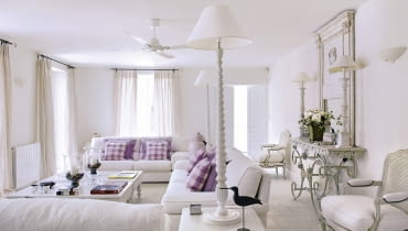 Salon Provencal holiday house with courtyard garden SLOWA KLUCZOWE: day colour building interior living room white sofa window curtain pole curtains animal bird chair mirror console table fresh coffee table purple cushion flooring radiator checked lilac overview furniture seating white room